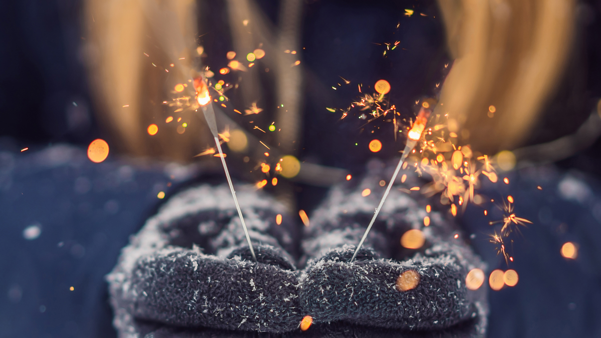 blue gloves holding sparklers on new years eve